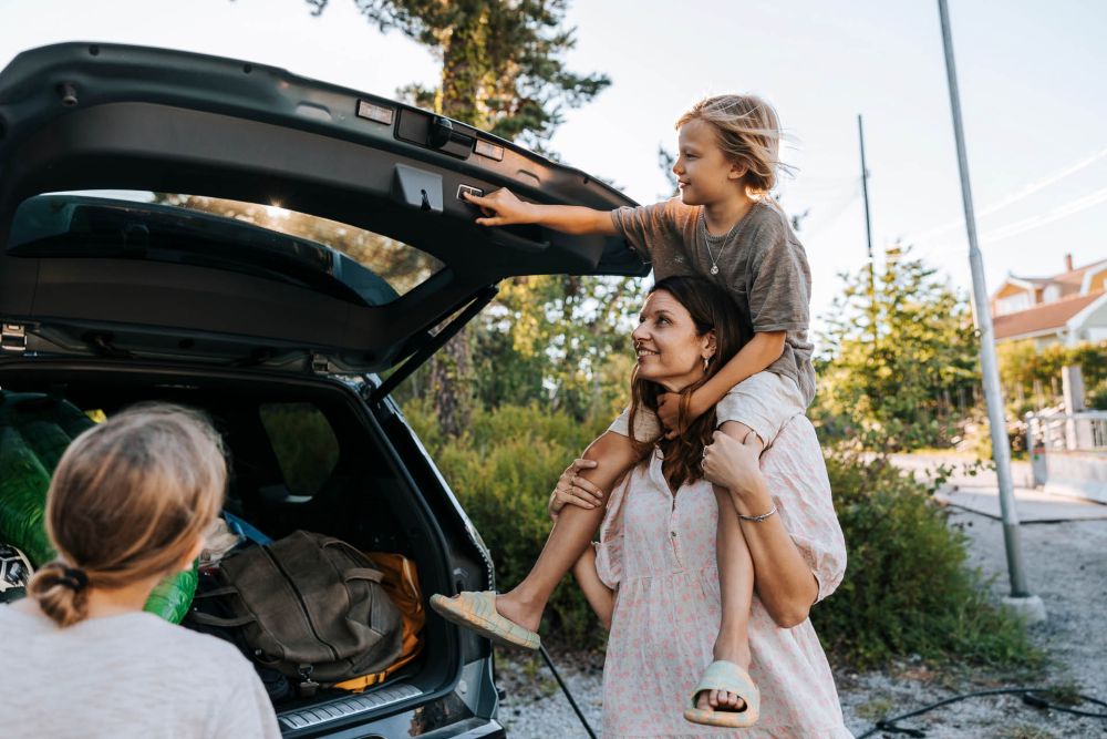 En familj packar in saker i bagaget på en bil