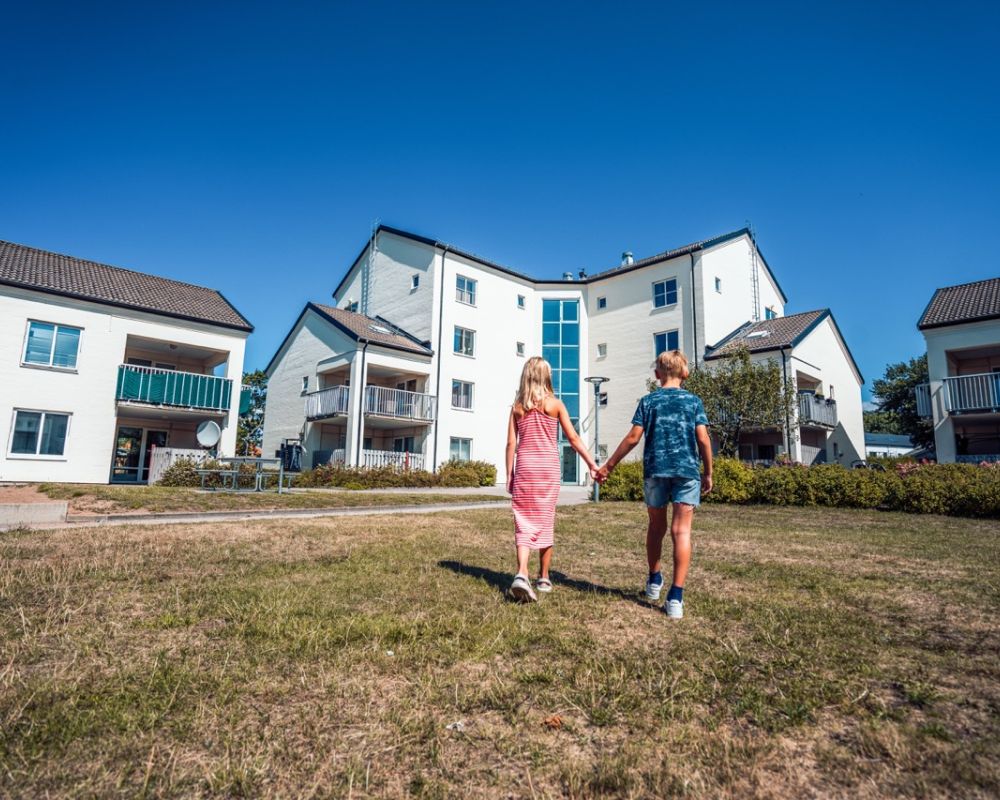 två barn håller hand vid ett bostadsområde