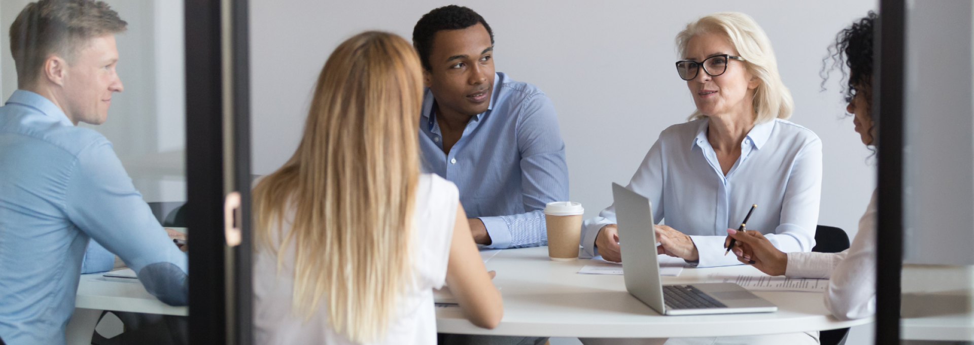 Fem personer sitter runt ett bord - pratar med varandra