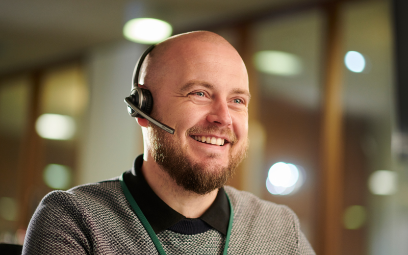 Glad man med headset, redo svara i telefon