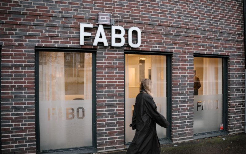 Fabos husfasad, kvinna går framför huset på trottoaren